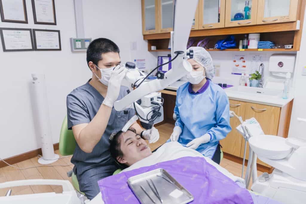 A dentist and assistant treating a patient with the dental operating microscope at Kitcha Dental Clinic