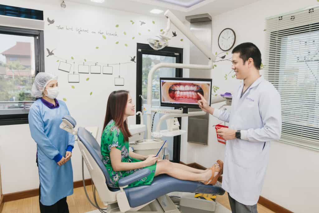 A dentist explaining a treatment plan on a screen to a patient in the dental chair at Kitcha Dental Clinic