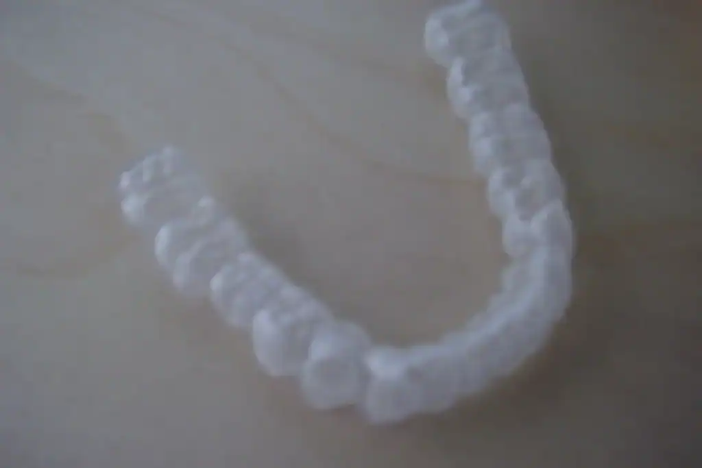 A clear occlusal splint for the lower teeth on a wooden surface