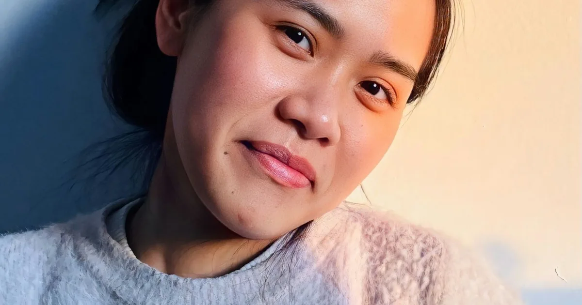一名亚洲年轻女士在温暖的傍晚光线中温柔微笑