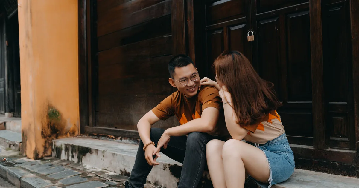 A young Asian couple sitting close together, smiling and chatting