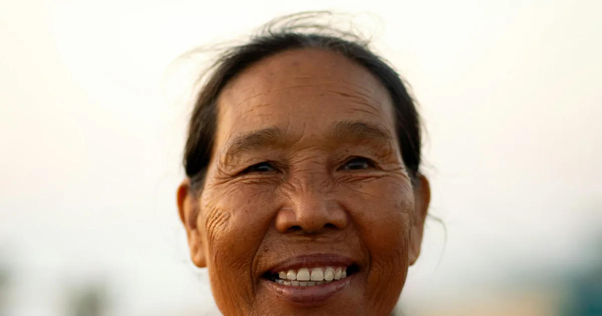 一位身穿紫色外套的亚洲年长女士温暖微笑