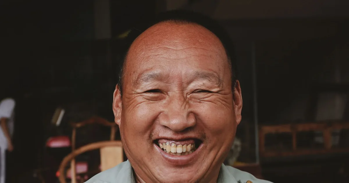 一位亚洲中年男士在室内开心地咧嘴微笑