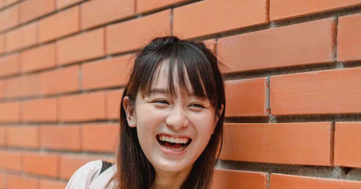 一位年轻的亚洲女性开怀大笑,笑容自然灿烂