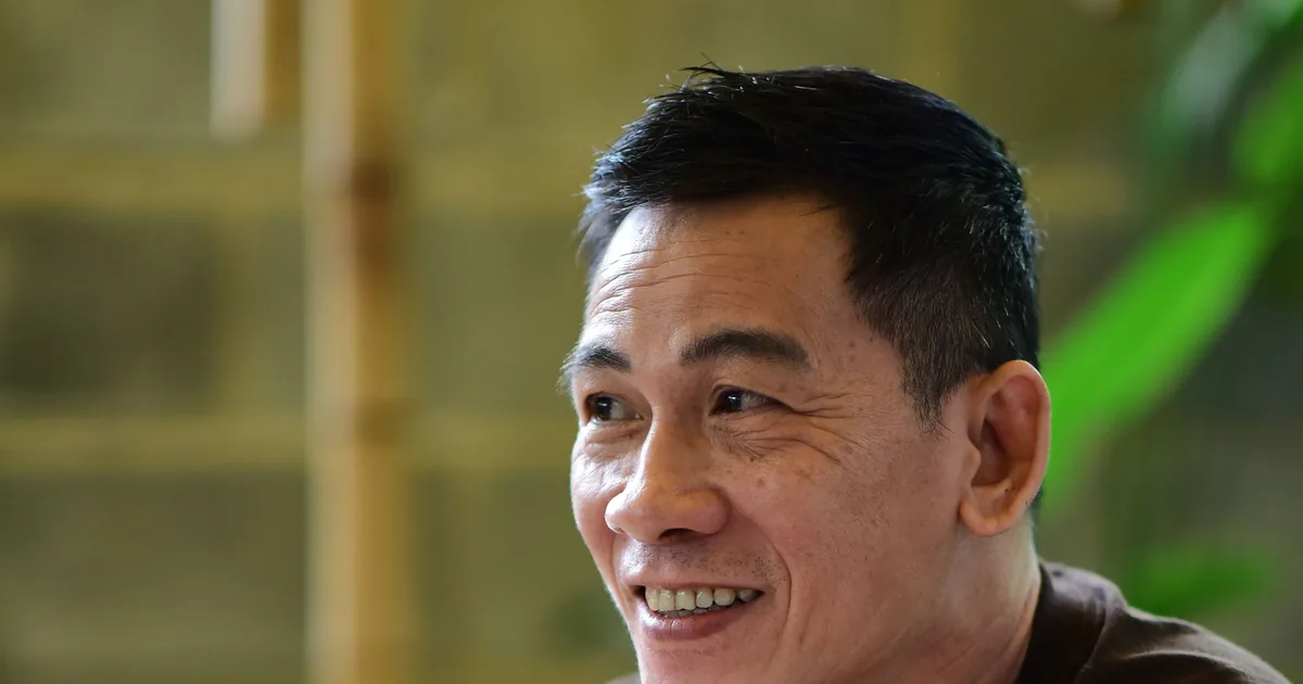 一名亚洲男士在咖啡馆里拿着手机,轻松微笑