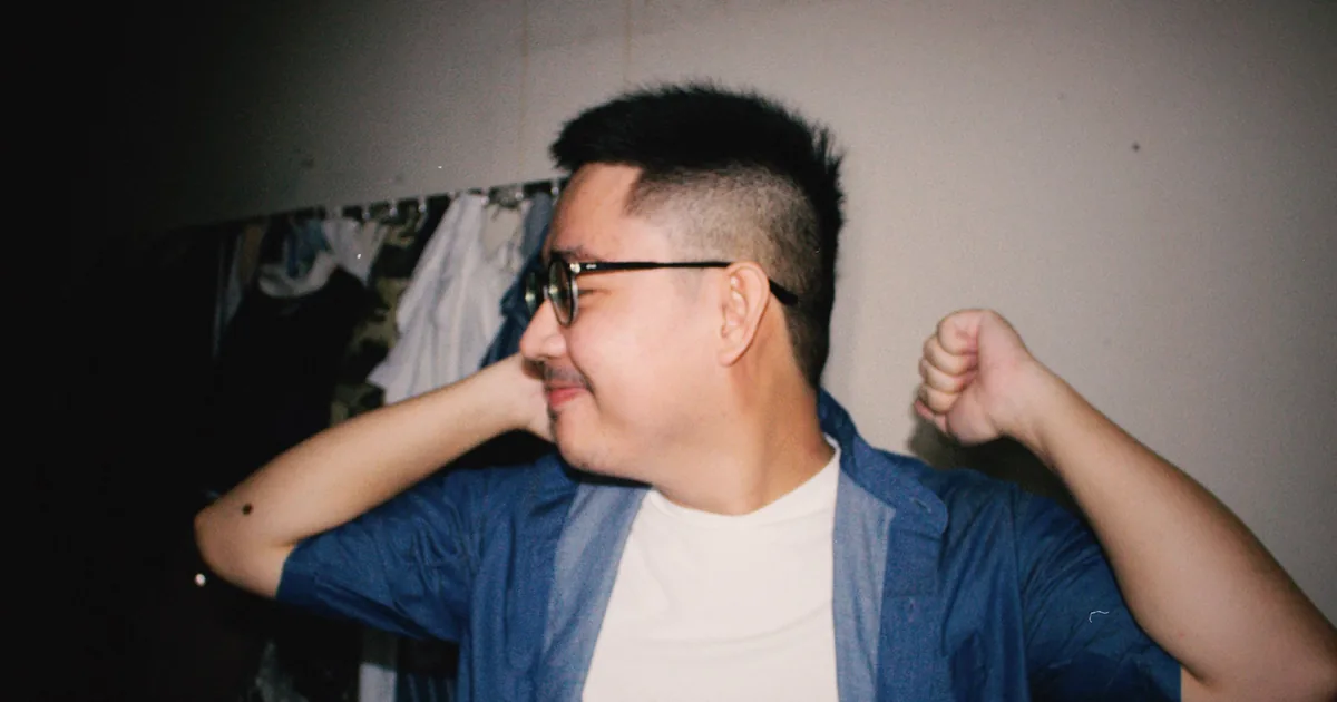 一名戴眼镜的亚洲年轻男士在室内放松微笑