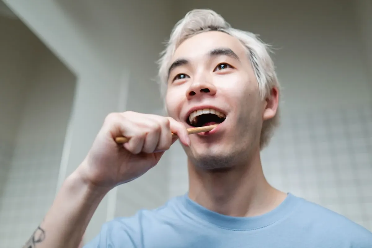 一名男士用竹柄牙刷刷牙,面带微笑