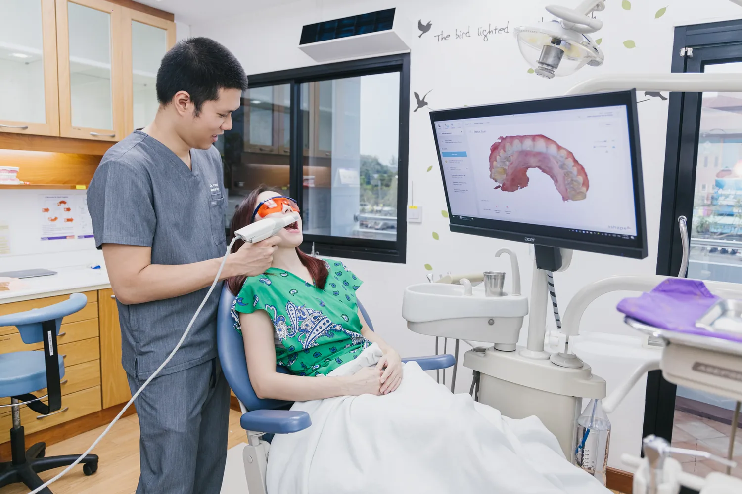 A dentist scanning a patients teeth with an intraoral scanner while the 3D scan appears on the screen
